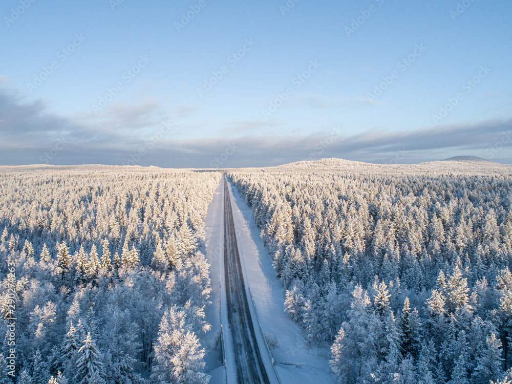 A straight road crossing northern boreal forest at winter in Lapland, Finland