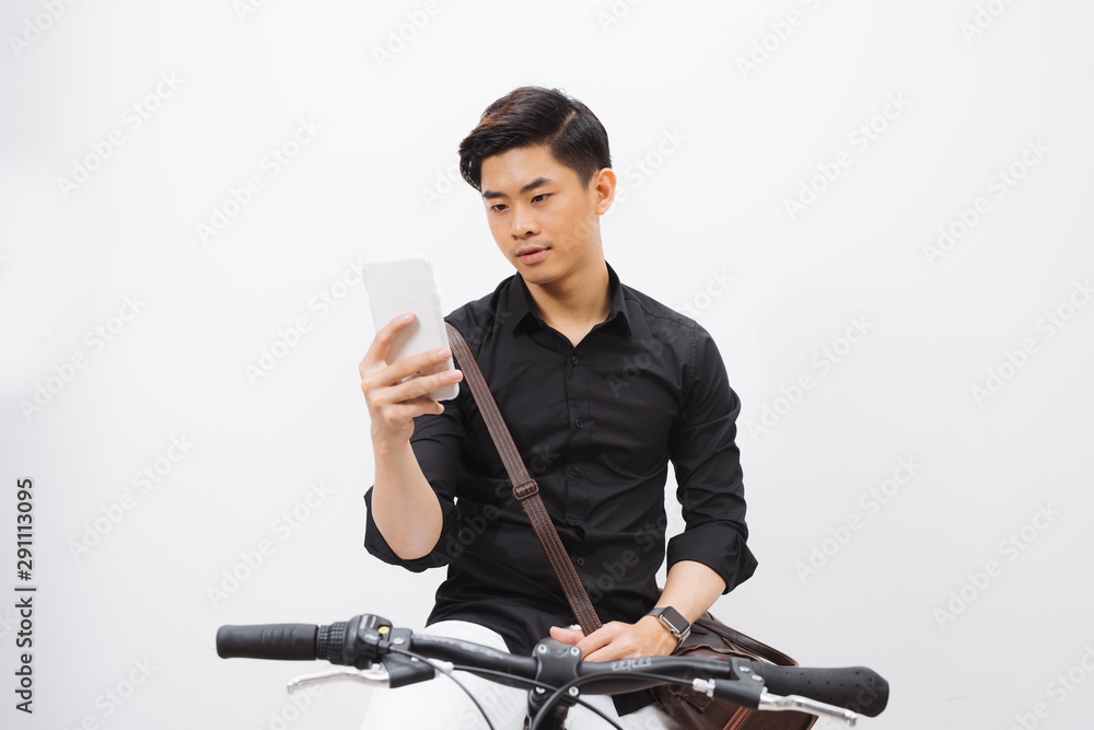 一名商人骑自行车上班时使用手机的照片