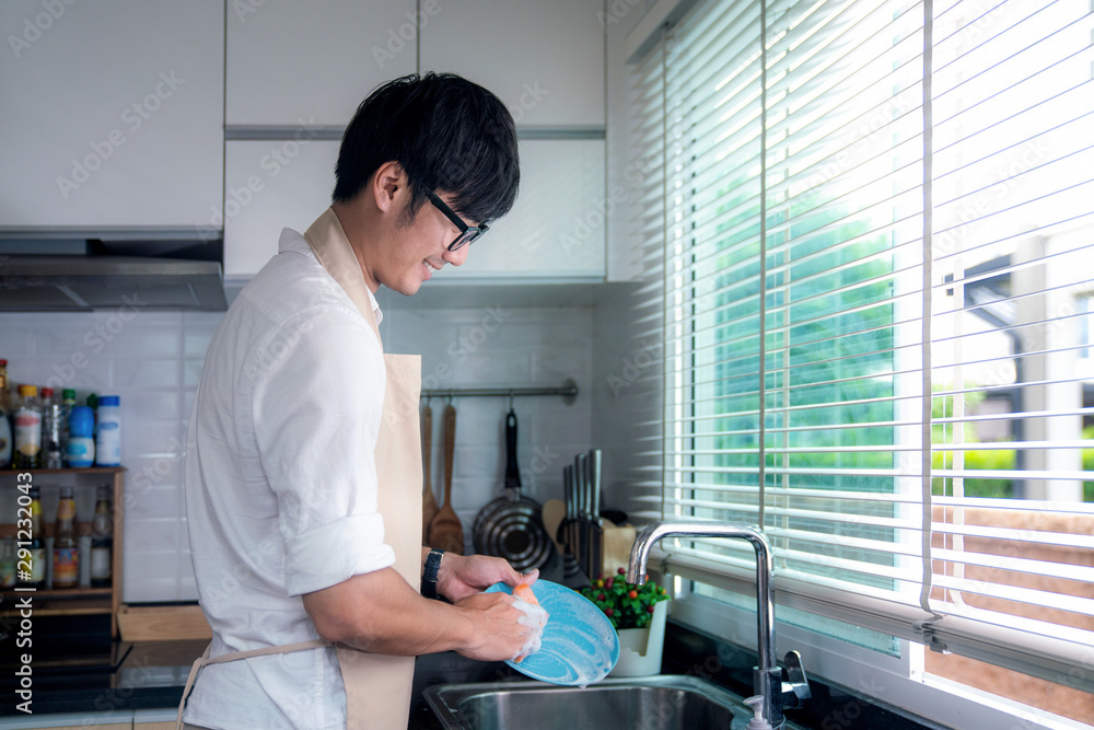 亚洲男子微笑着在厨房洗碗