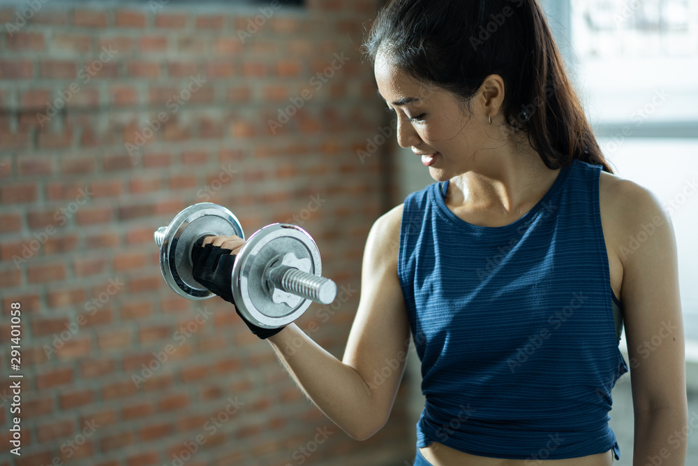 亚洲女性在健身房锻炼。举重