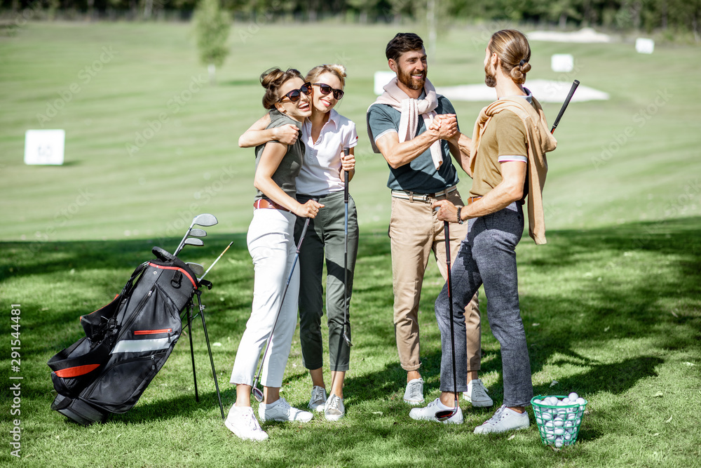 年轻优雅的朋友在比赛前在高尔夫球场上聚会，在阳光明媚的日子里一起玩得很开心