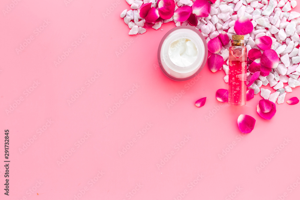 粉色背景上带有海盐和玫瑰装饰的化妆品顶部视图空间用于文本