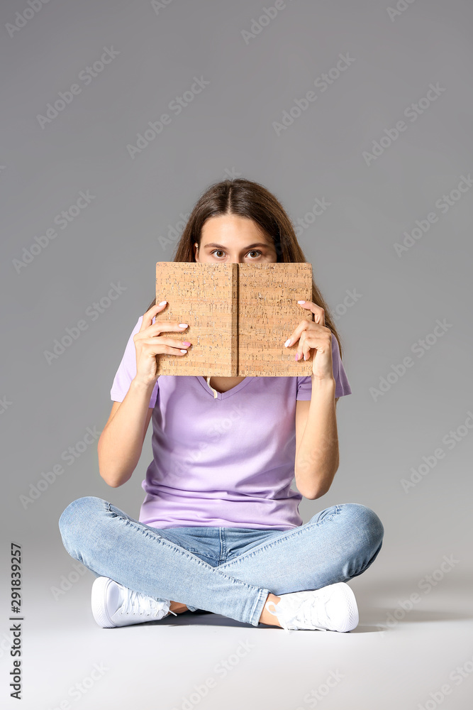 灰色背景下拿着书的年轻女孩