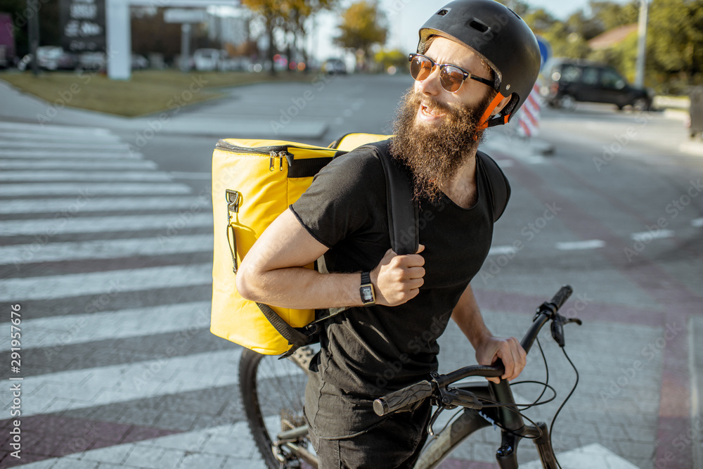 一名男性快递员骑着自行车在城市的骏马上行走，用黄色的保温袋运送食物的肖像