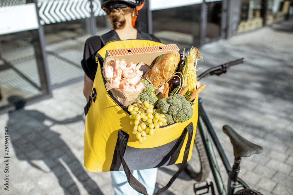 女快递员背着装满新鲜产品的背包，送杂货和鲜花。fresh pro