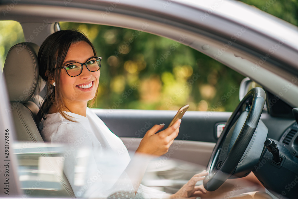 一位年轻女司机在车里使用智能手机和gps导航的肖像。
