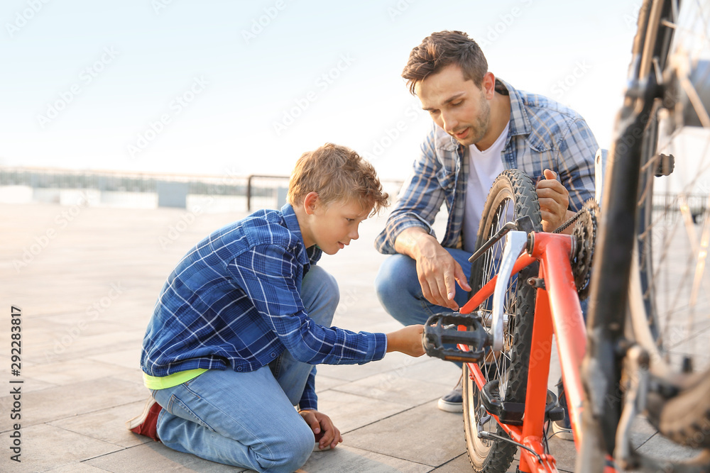 父亲和儿子在户外修理自行车
