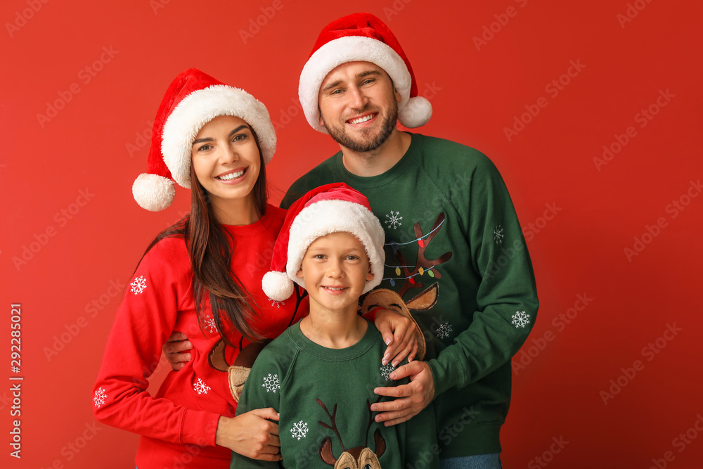 Happy family in Christmas sweaters and Santa hats on color background