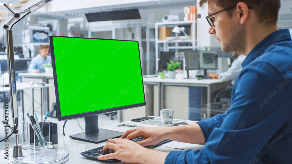工程师在台式电脑上使用绿屏实体模型模板的肩扛镜头。I