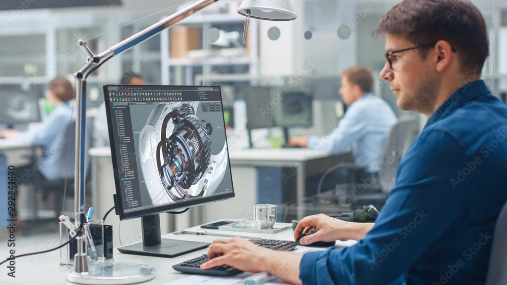 工程师在台式电脑上使用CAD软件的肩上镜头，屏幕显示技术