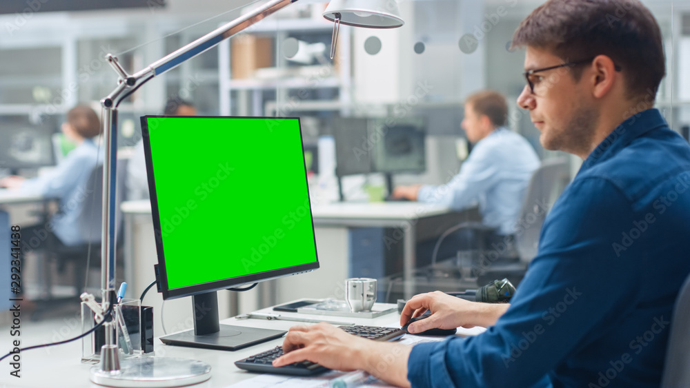 工程师在后台使用绿色实体屏幕台式电脑的肩扛镜头