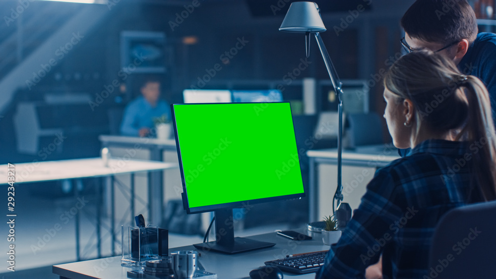 在台式电脑上工作的工程师，屏幕显示绿色实体屏幕，她的男项目经理
