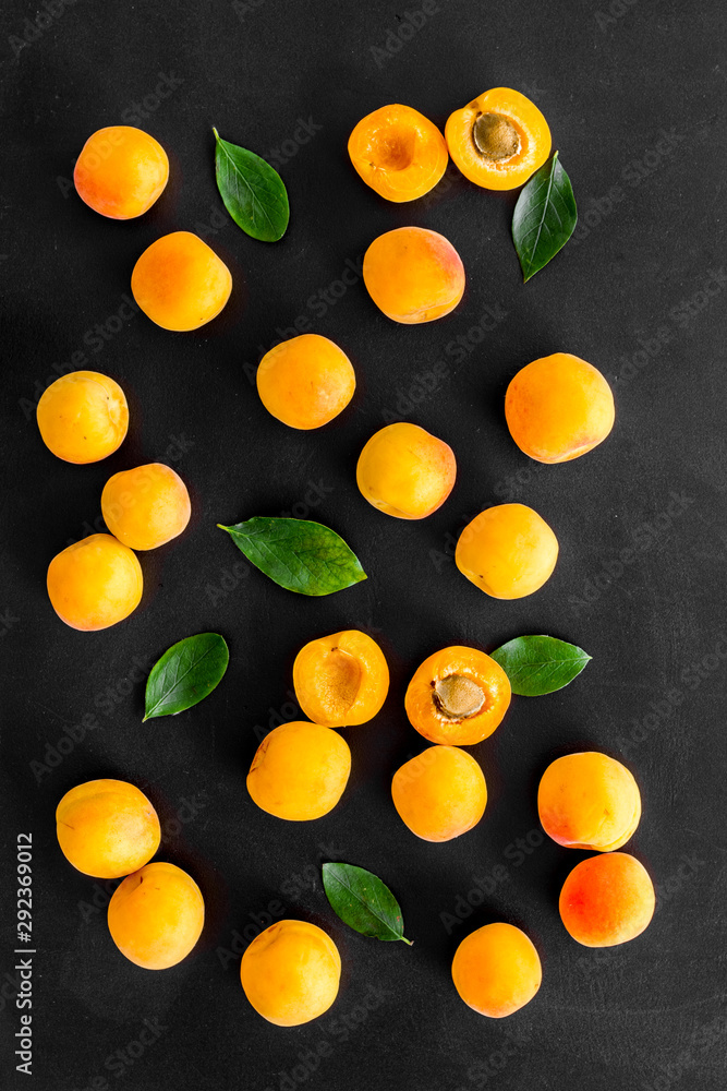 Apricots and leaves pattern on black background top view