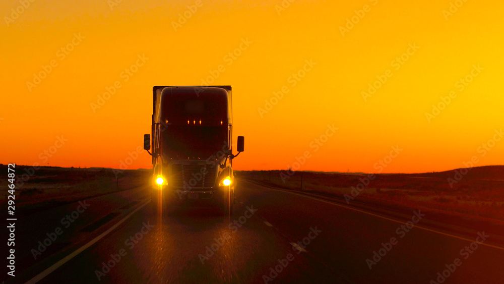 特写镜头FLARE：金色日落时，半卡车直接驶入镜头