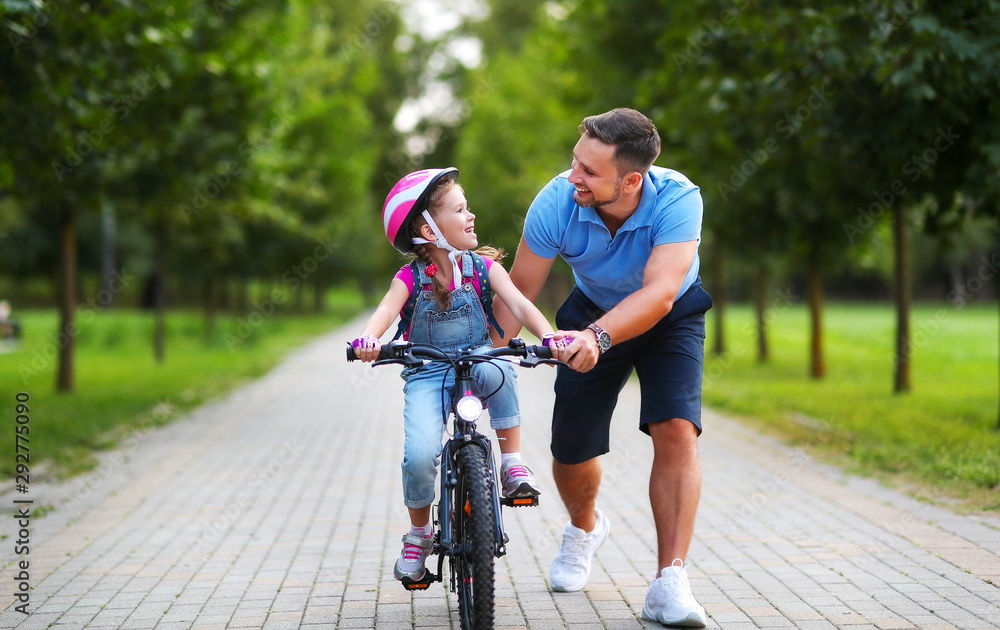 幸福家庭的父亲教孩子女儿在公园里骑自行车