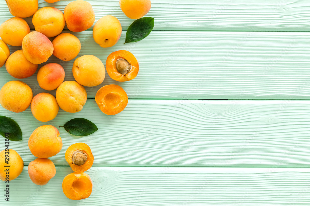 水果框架。绿色木质背景上的杏子和树叶用于文本俯视空间