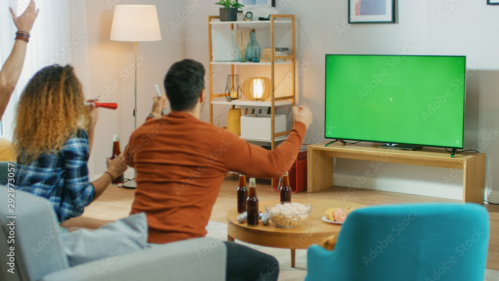 三名体育迷坐在客厅的沙发上观看绿色Chroma键屏电视重要M