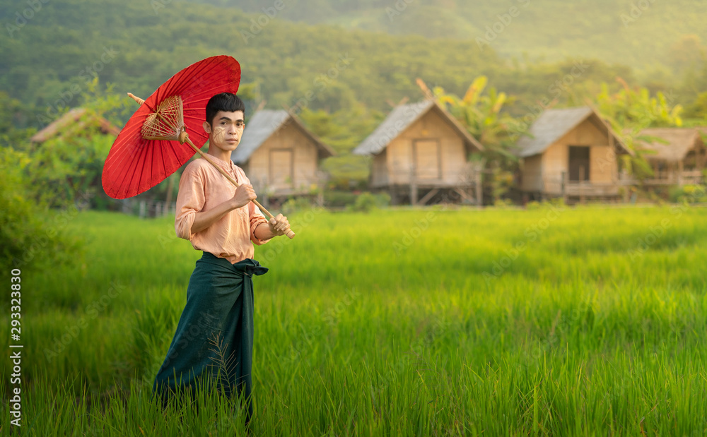 穿着传统缅甸风格的男子在田野里撑着伞的肖像。亚洲，缅甸。