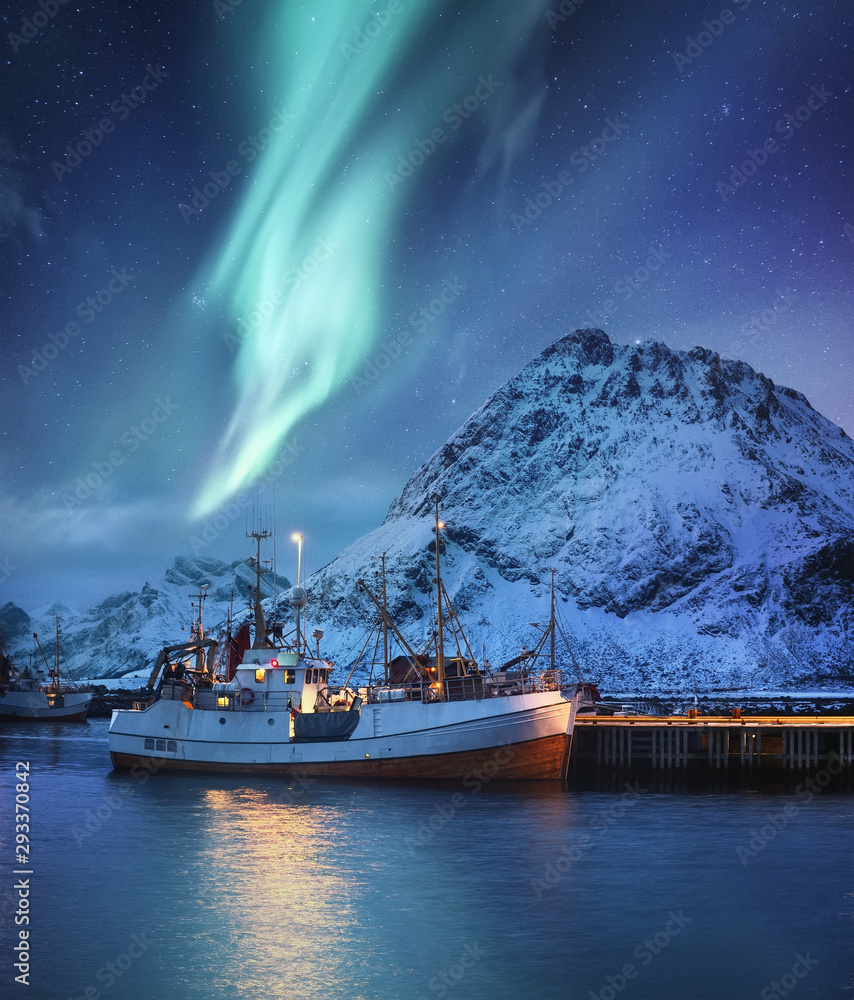 挪威罗弗敦群岛的北极光、山脉和渔船。冬季景观
