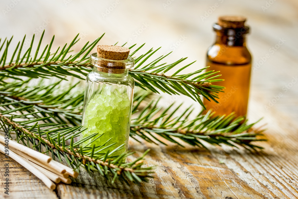 云杉针芳香疗法精油和盐装在木桌背景上的瓶子里
