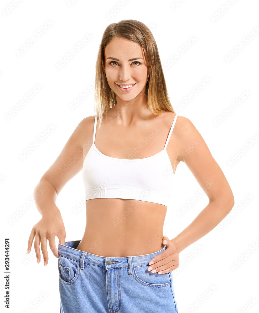 美丽的年轻女子穿着白色背景的宽松牛仔裤。减肥概念