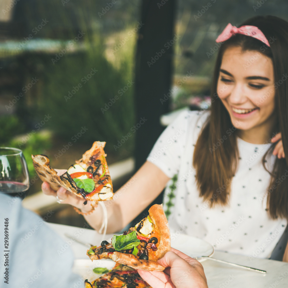 在意大利，一对年轻幸福的高加索夫妇坐在桌子旁吃着新鲜出炉的披萨，喝着葡萄酒