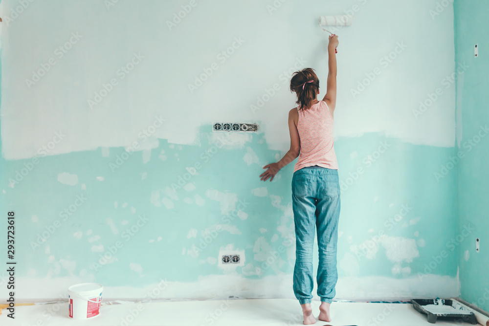 Preteen child painting the wall in her room in blue and white colors. Young girl making interior ren