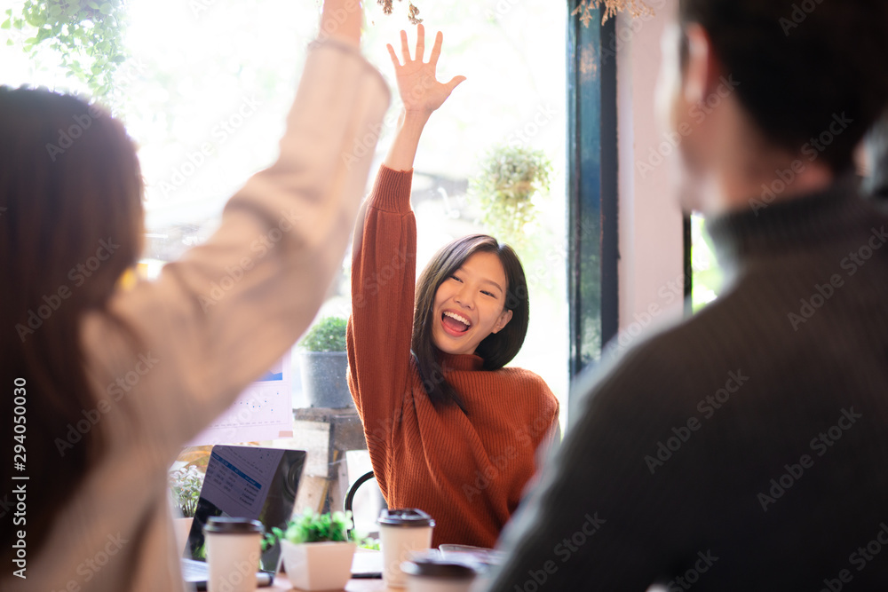 亚洲女性和她的团队为与团队在咖啡馆取得圆满成功而举手