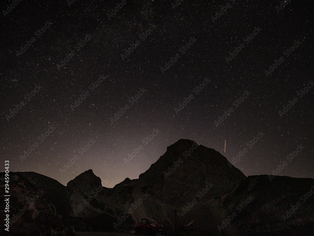 一颗流星冲向岩石山脉上方的夜空
