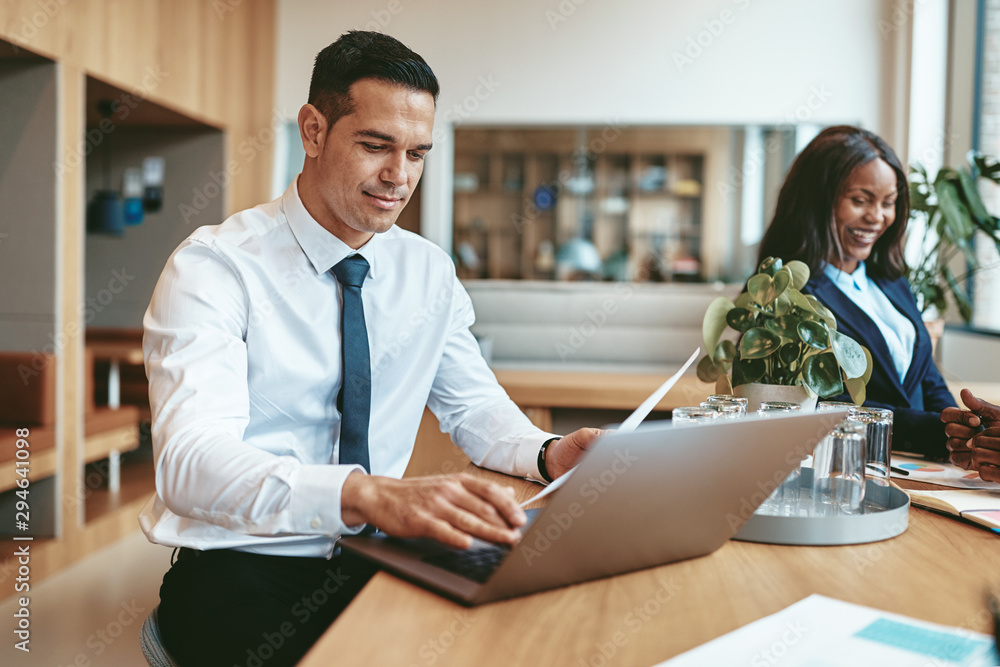 微笑的商人在现代办公室里用笔记本电脑工作
