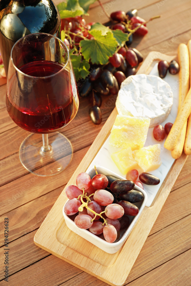 木桌上放着一杯葡萄酒和一瓶小吃