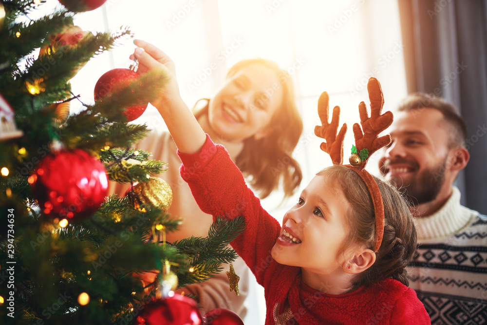 幸福的家庭母亲、父亲和孩子的女儿装饰圣诞树。