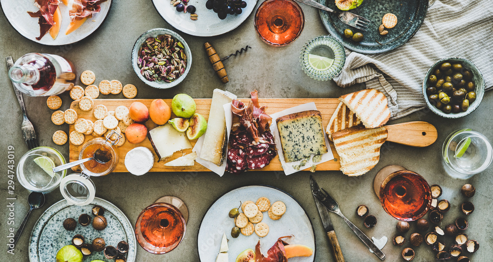 仲夏野餐，有葡萄酒和小吃。平坦的熟食和奶酪板，瓶装玫瑰酒