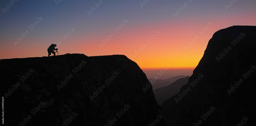 SILHOUETTE：摄影师准备他的设备来捕捉阿尔卑斯山的日落。
