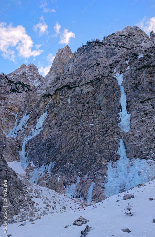 无人机：阿尔卑斯人聚集在一条从山上流下来的冰冻河流下攀登