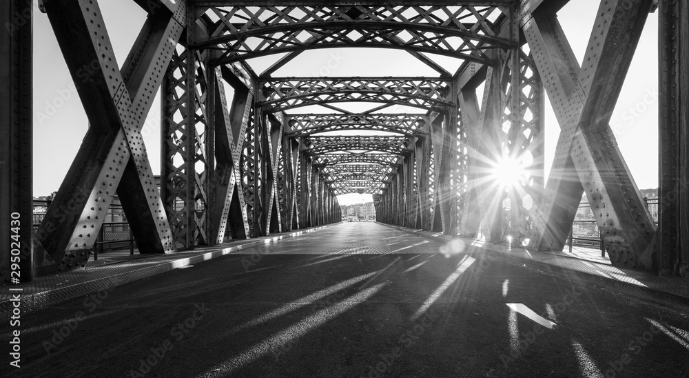 阳光明媚的日子里，城市一座桥梁钢结构下的黑白柏油路。Ev
