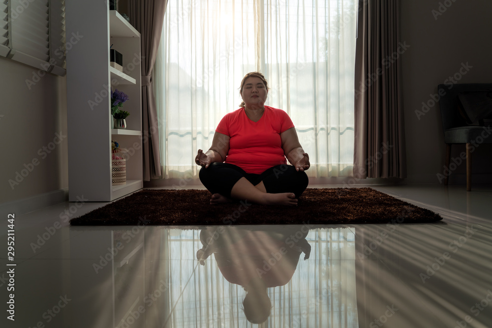 亚洲超重女性独自在家里的地板上锻炼瑜伽简易姿势，瑜伽冥想练习
