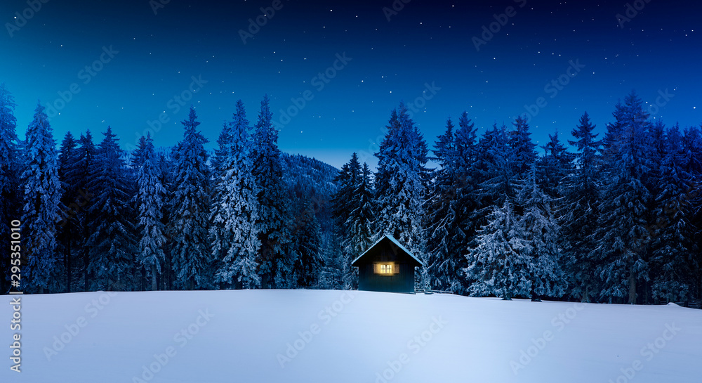 Blockhütte mit Leuchtendem Fenster in winterlichem Wald