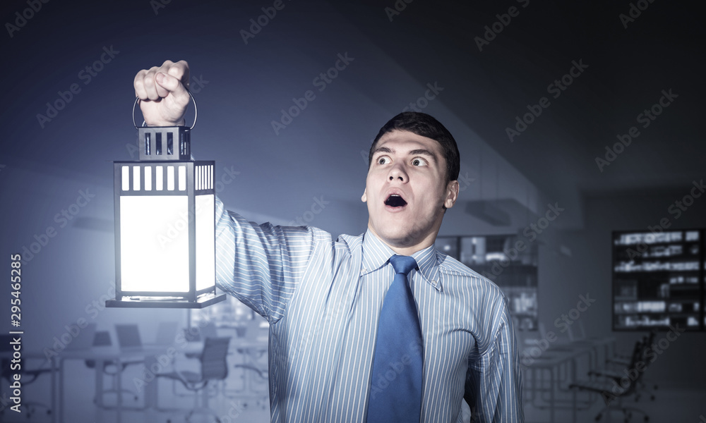 Horrified businessman holding glowing lantern