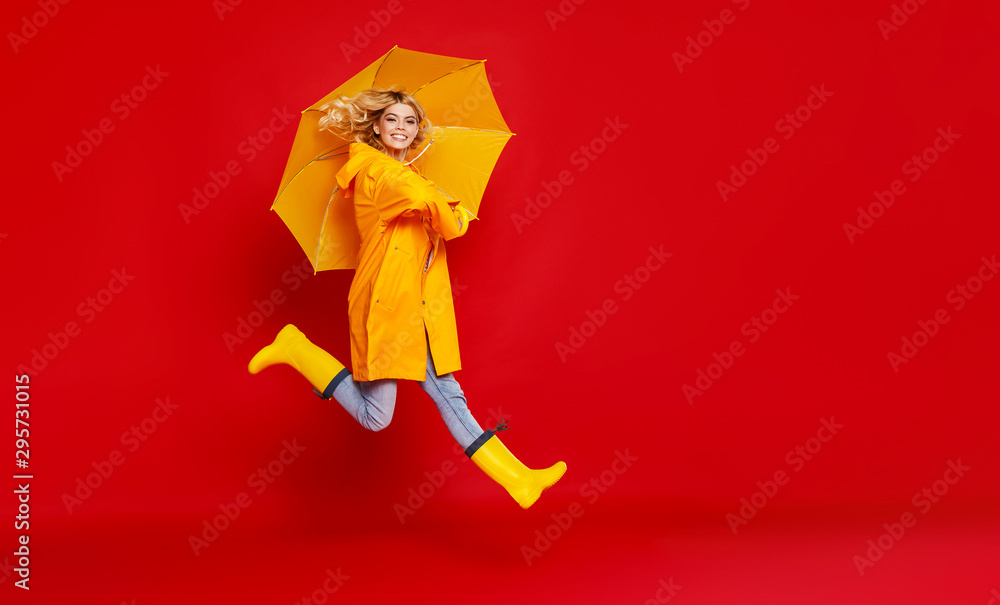 年轻快乐、情绪愉悦、开朗的女孩，黄色雨伞撑在彩色红色的背上，笑着跳着