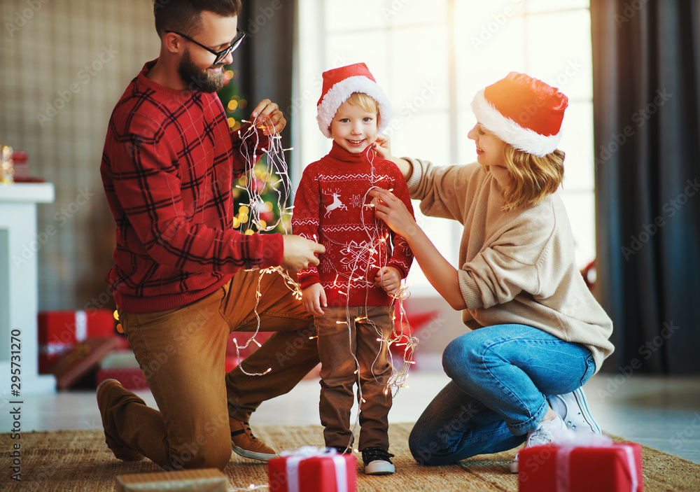 幸福的家庭装饰圣诞树，父母带着花环和儿子玩耍。