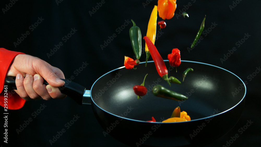 Closeup of chef holding frying with falling chilli peppers