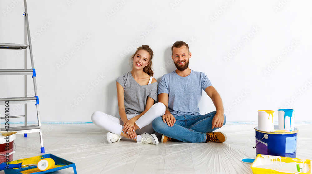 一对幸福的年轻夫妇正在家里修理和粉刷墙壁
