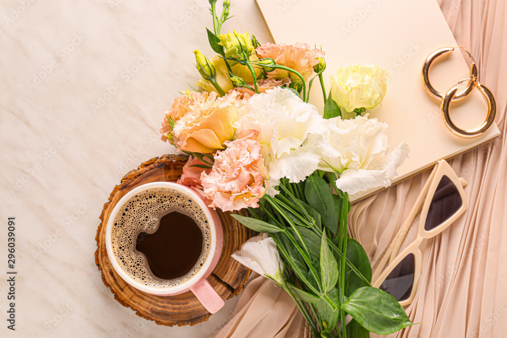 Eustoma花朵配一杯咖啡、笔记本和浅色背景的女性配件