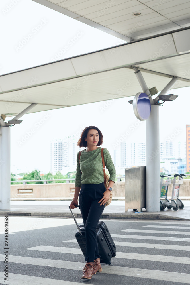 年轻可爱的亚洲女人带着行李在机场旅行