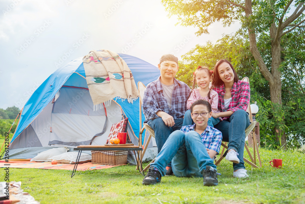 快乐的亚洲家庭一起坐在露营地的帐篷前。
