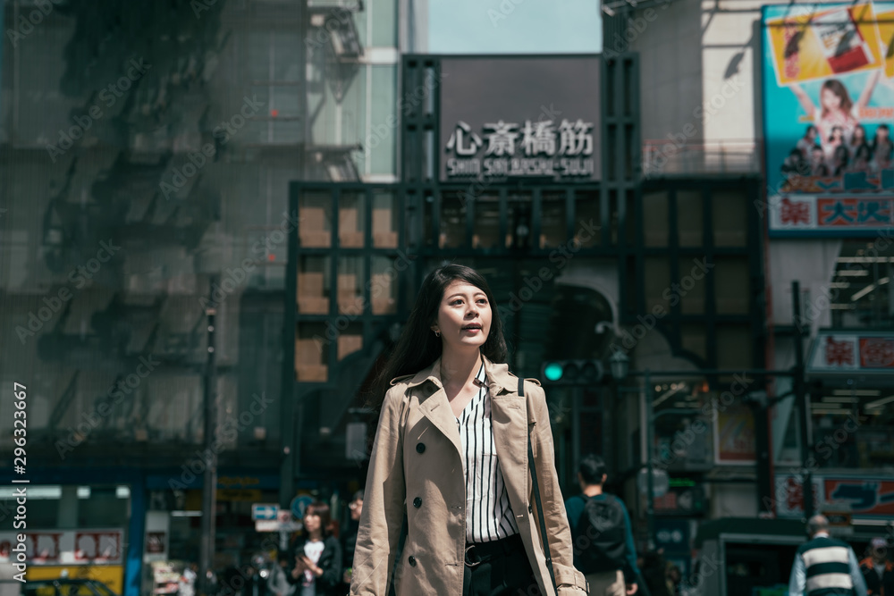 年轻漂亮的亚裔日本女人穿着外套走在繁忙的街道上春天的户外。灿烂的笑容