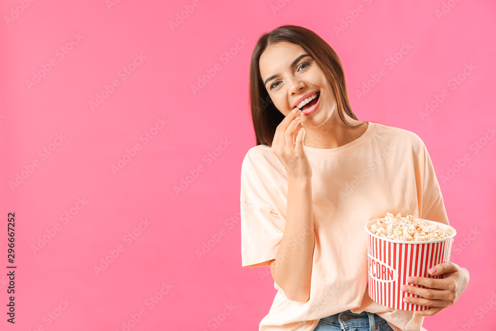 年轻女子在彩色背景下吃爆米花