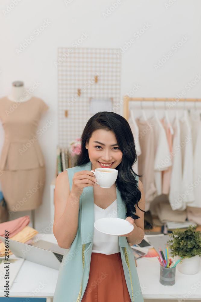 年轻的时装设计师在她的工作室里停下来喝咖啡