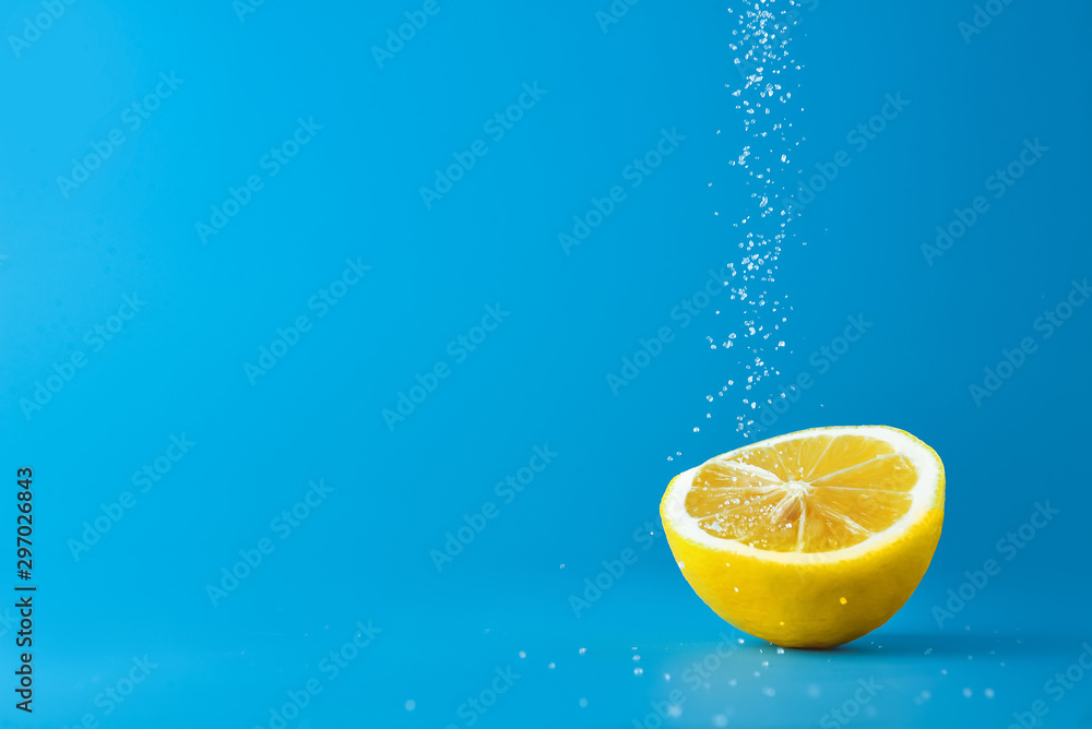 在彩色背景下将糖撒在新鲜柠檬上